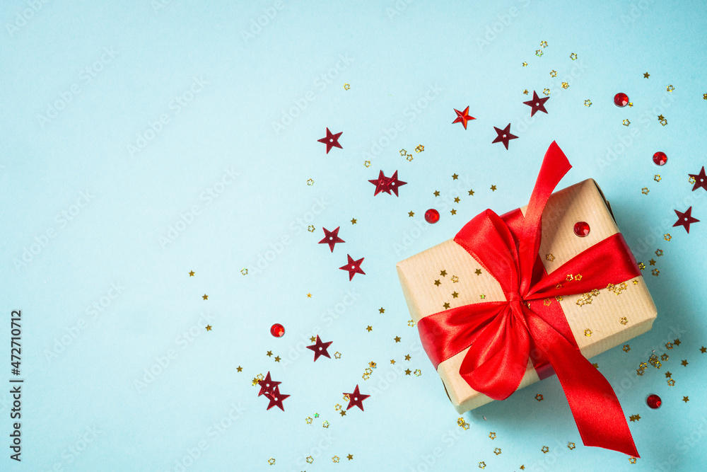 Christmas present box with red ribbon and glitter. Flat lay image on blue. Christmas present box with red ribbon and glitter. Flat lay image on blue.