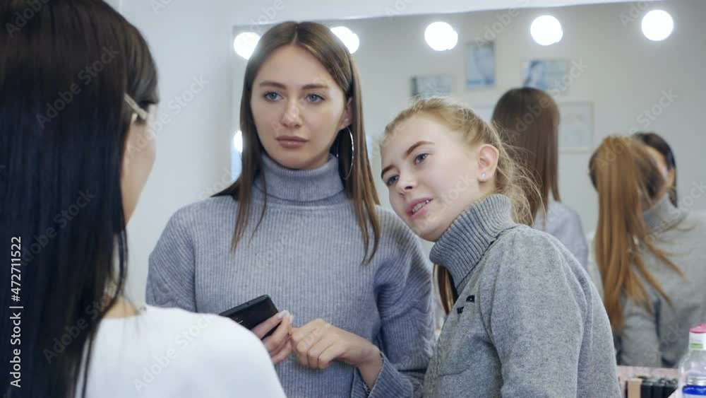 Young female professional makeup artist teaching her young student to become a makeup artist in a master class in a beauty salon Young female professional makeup artist teaching her young student to become a makeup artist in a master class in a beauty salon