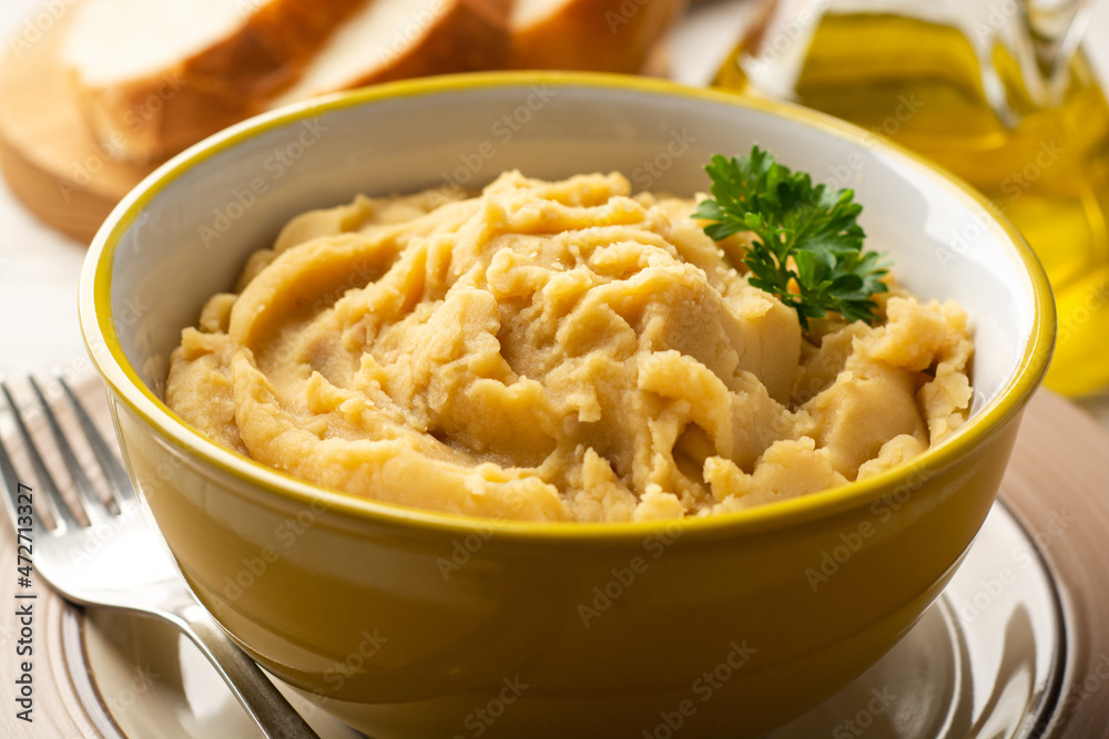 Yellow pea puree or porridge or pudding in bowl on white wooden rustic background
