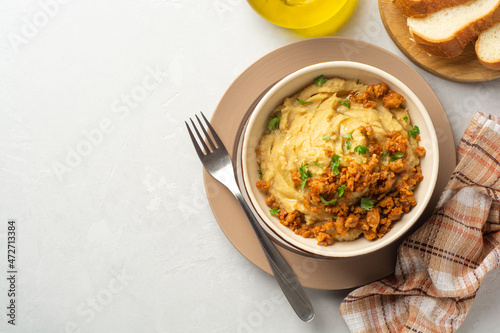 Yellow pea puree or porridge or pudding with meat sauce in bowl on concrete background