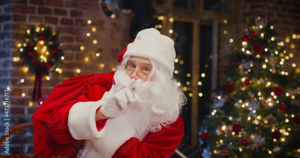 Waist up portrait view of the happy senior man in Santa Clause costume holding bag with presents while spending time at home. Holidays concept Waist up portrait view of the happy senior man in Santa Clause costume holding bag with presents while spending time at home. Holidays concept