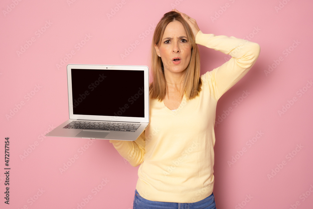 Naklejka premium Young amazed woman wearing casual clothing laptop computer screen standing isolated over pink background.