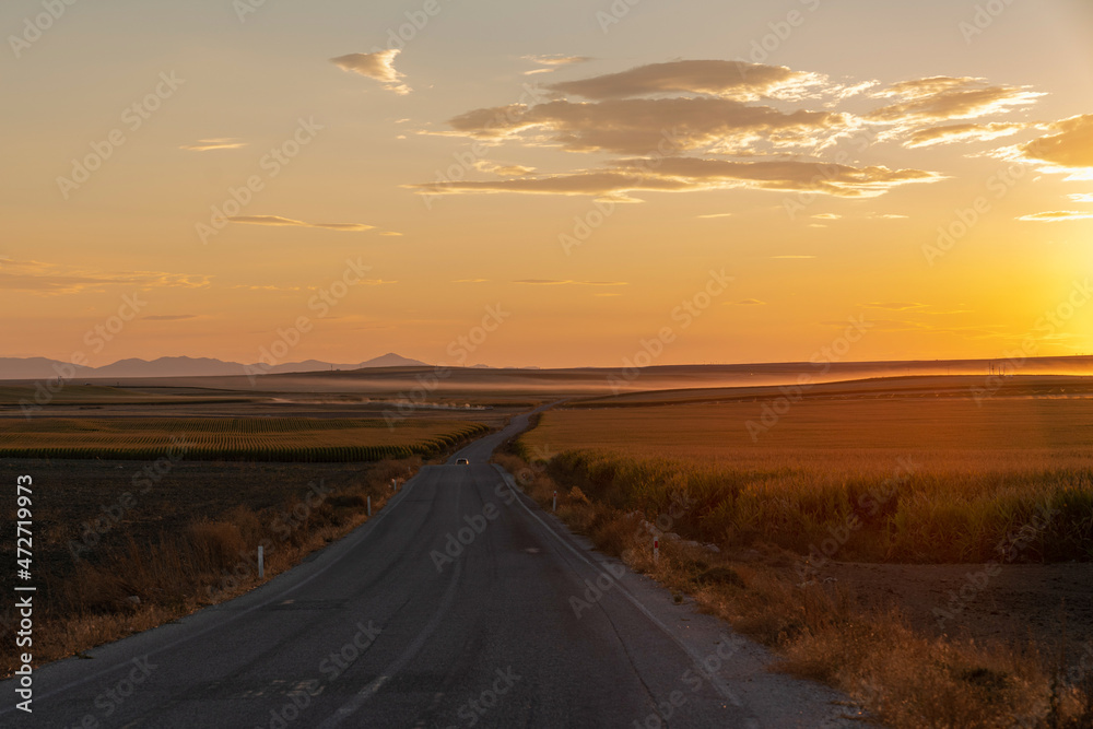 Asphalt road between fields and sunset in the background. Konya, Turkey. Asphalt road between fields and sunset in the background. Konya, Turkey.