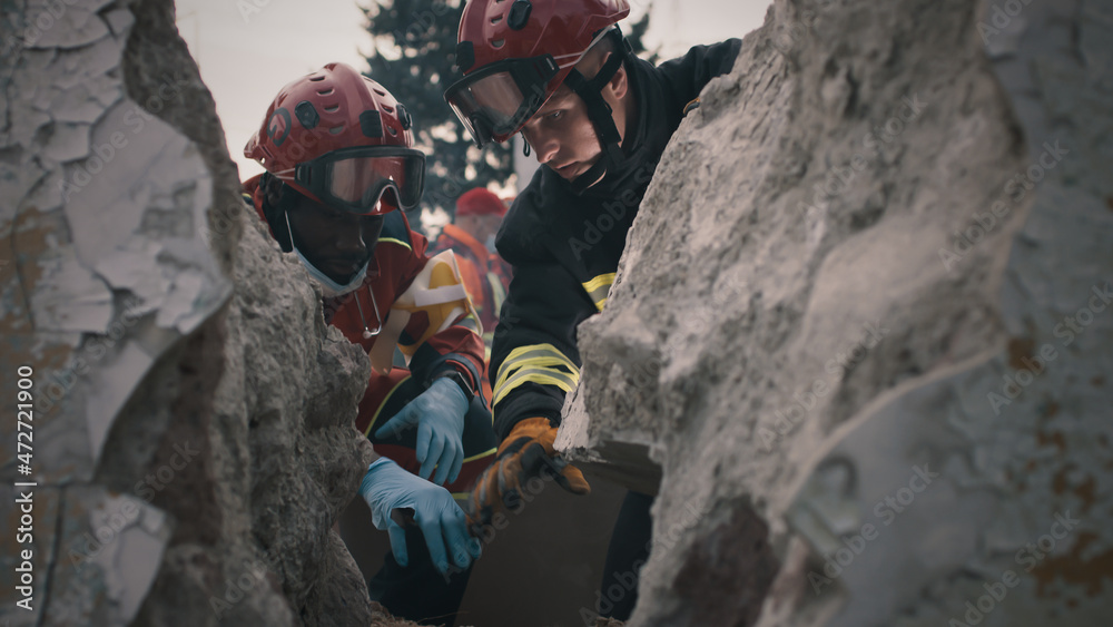 Αυτοκόλλητο Black rescuer talking with colleague while sitting near rubble and rescuing surv