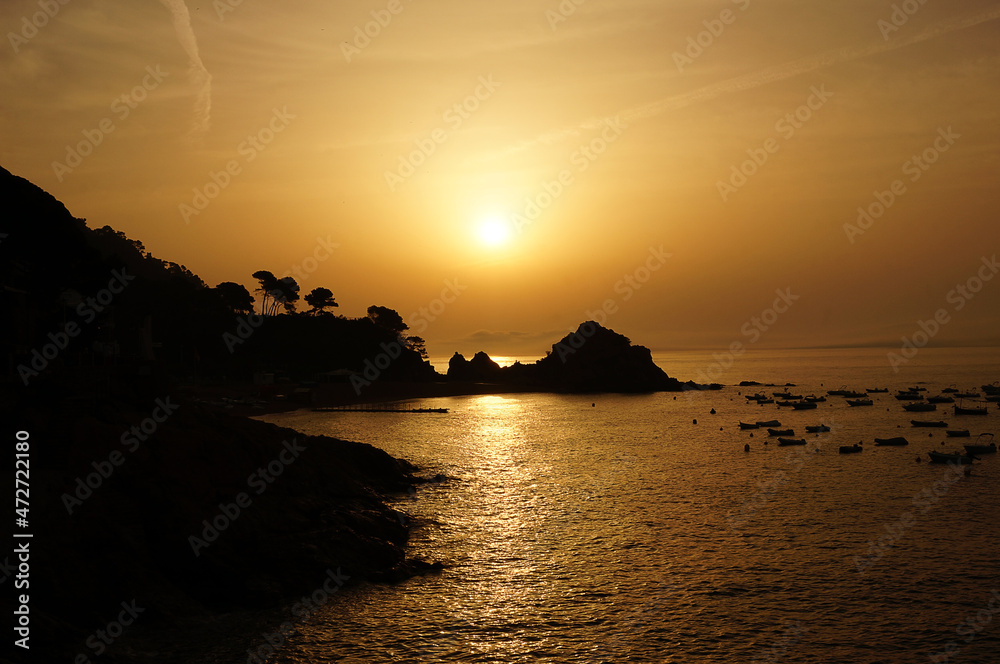 sunrise over the sea on the background of rocks in summer in Spain in Tossa de mar in yellow tones