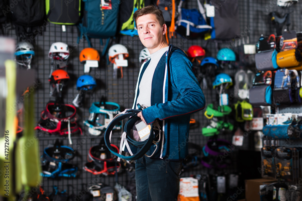 Young smiling man chooses the gear for sports in store