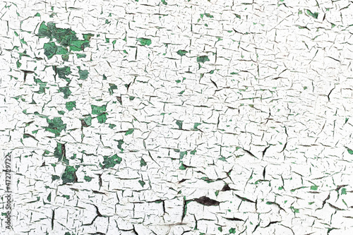 White paint peeling off green surface.