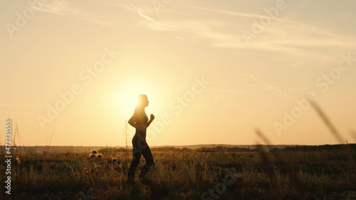 Healthy jogging and outdoor exercise concept. Jogging workout in the sun. Young woman in summer runs through the park at sunset. Goes in for sports at dawn. Run after the sun. Autumn training