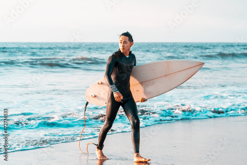 surfer walking on the beach with a surfboard 