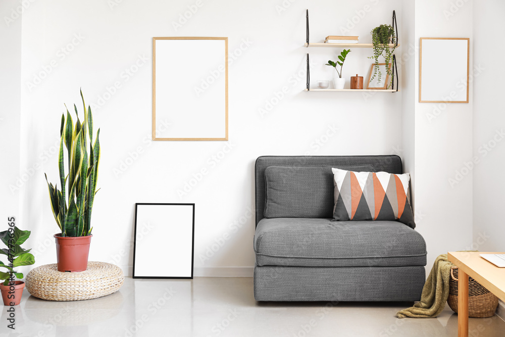 Interior of modern stylish room with armchair near light wall with blank posters Interior of modern stylish room with armchair near light wall with blank posters