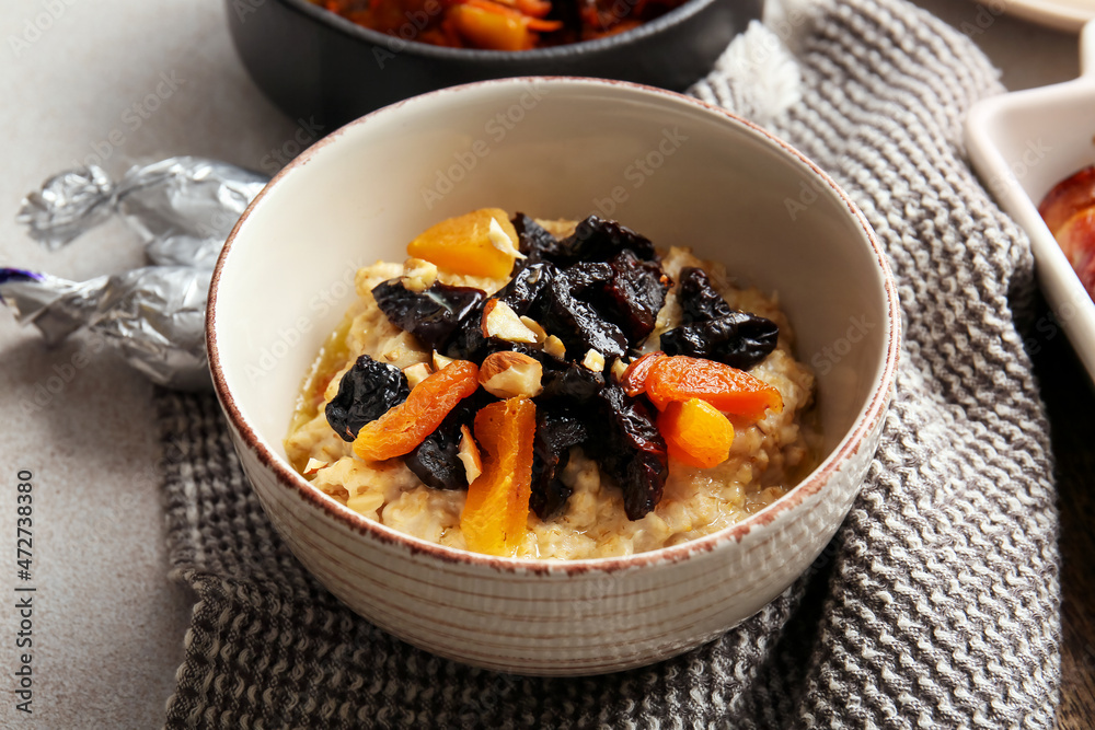 Tasty sweet oatmeal with prunes, dried apricots and almond nuts in bowl