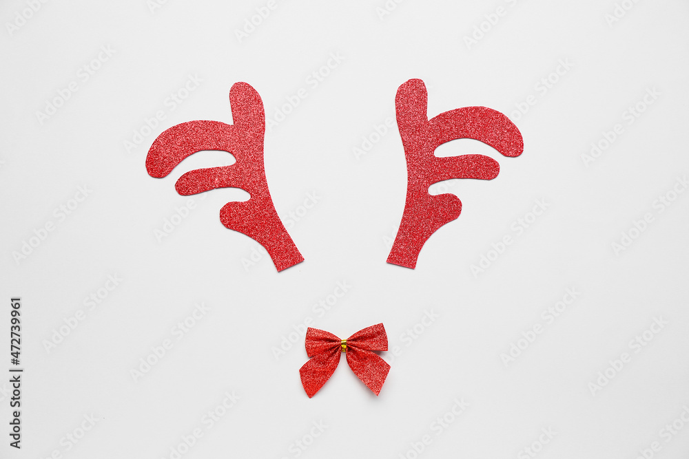 Composition with toy reindeer horns and bow on grey background Composition with toy reindeer horns and bow on grey background
