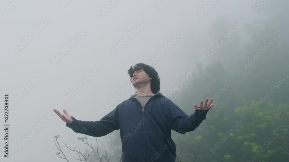 Male traveller flicks hair at the top of mountain with thick fog in the early morning in the background. Lifestyle on vacation. Male traveller flicks hair at the top of mountain with thick fog in the early morning in the background. Lifestyle on vacation.