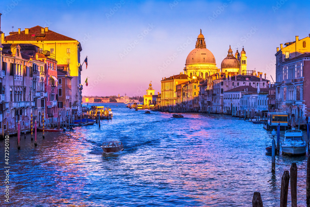 Colorful Grand Canal and Santa Maria della Salute church under sunset with reflection in Venice, Italy.