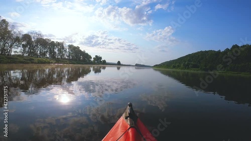 Red kayak went down a river with sun reflection. River travel landscape