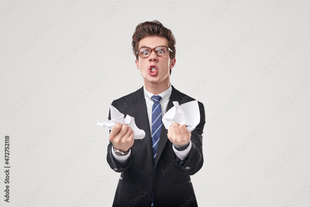 Angry businessman crumpling documents in studio Angry businessman crumpling documents in studio