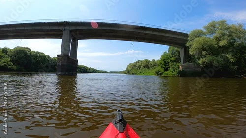 Kayak went down summer river under the stone bridge. 