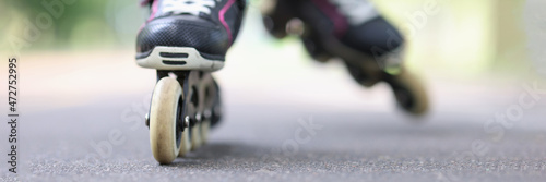 Foto Child riding black rollerblades on road closeup