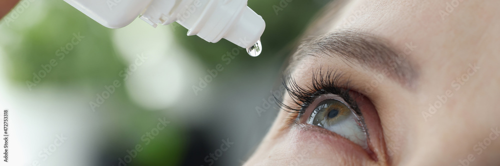 Woman dripping into her eyes with antibacterial drops closeup