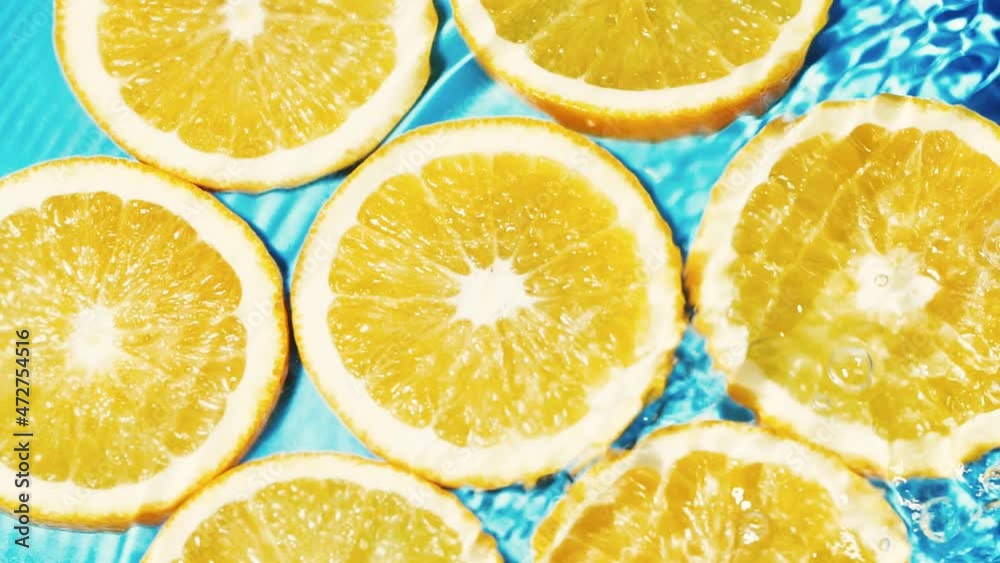 Macro orange fruit slices and blue water surface texture with ripple and splash Macro orange fruit slices and blue water surface texture with ripple and splash