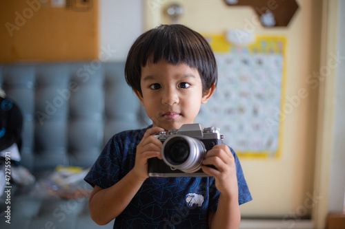 Little asian boy hold camera learn to take photo