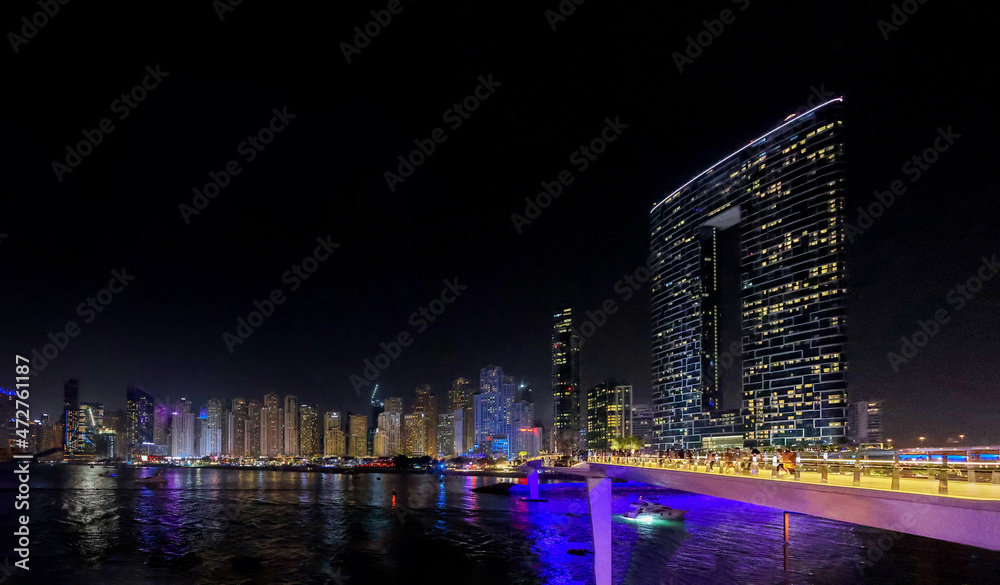 Fototapeta premium Panoramic view at night of Business Bay district with reflection in sea, UAE. Aerial sky at highest buildings in central Dubai, United Arab Emirates. High quality photo