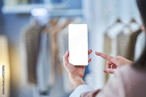 Woman holding phone in clothes store with blank space