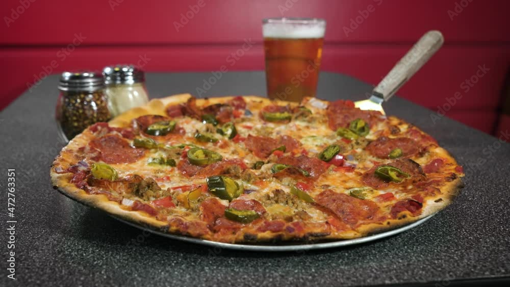 Classic Pepperoni pizza in grey pizzeria table top paired with pint of