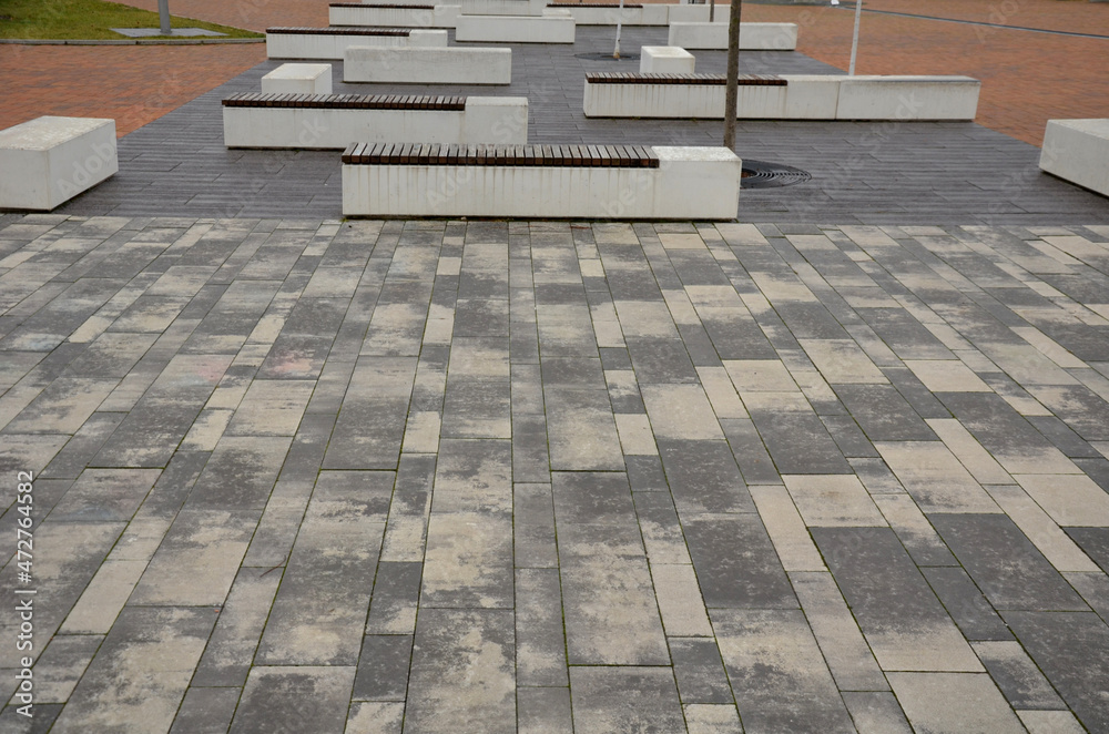 concrete white bench block and wave shape in the park on a dark cobbled square, clean concrete surface gray brown white pedestrian and rest area at the skate park for young people, teenagers