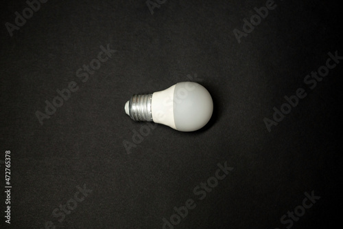 white light bulb base lies on a black isolated background