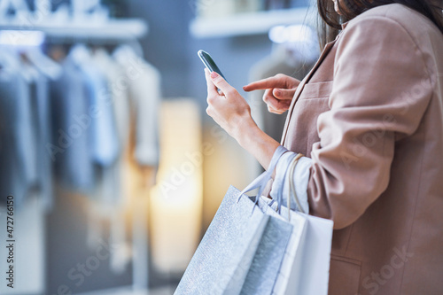 Billede på lærred Nice woman with phone in clothes store
