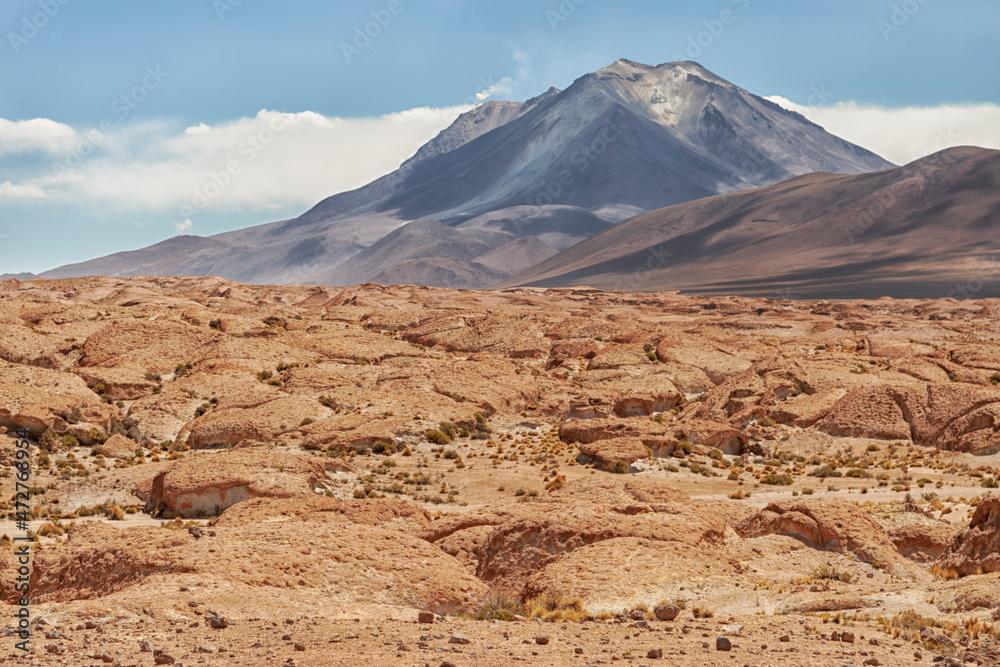 Bolivia, Atacama Desert. An active volcano rises above an old lava field.