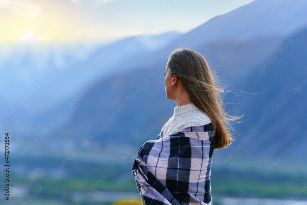 Serene peaceful woman wrapped in a blanket standing alone in thoughts and looking into the distance.Female enjoying freedom and calm Serene peaceful woman wrapped in a blanket standing alone in thoughts and looking into the distance.Female enjoying freedom and calm