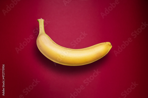 Delicious fresh banana with shadow on red background.