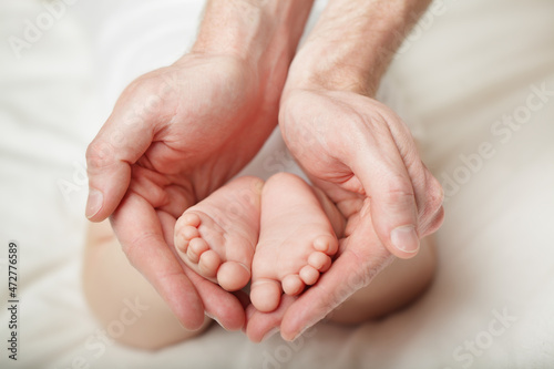 Baby feet cupped into father hands © millaf