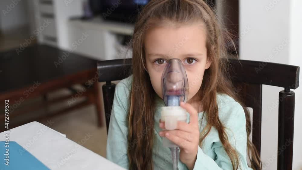Little girl sit on chair and hold breathing mask on face. Portable