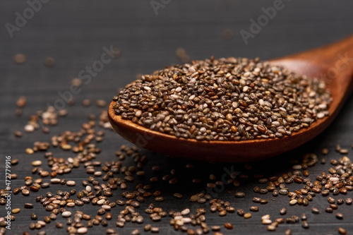 Bowl of organic natural chia seeds close-up on wooden background or table