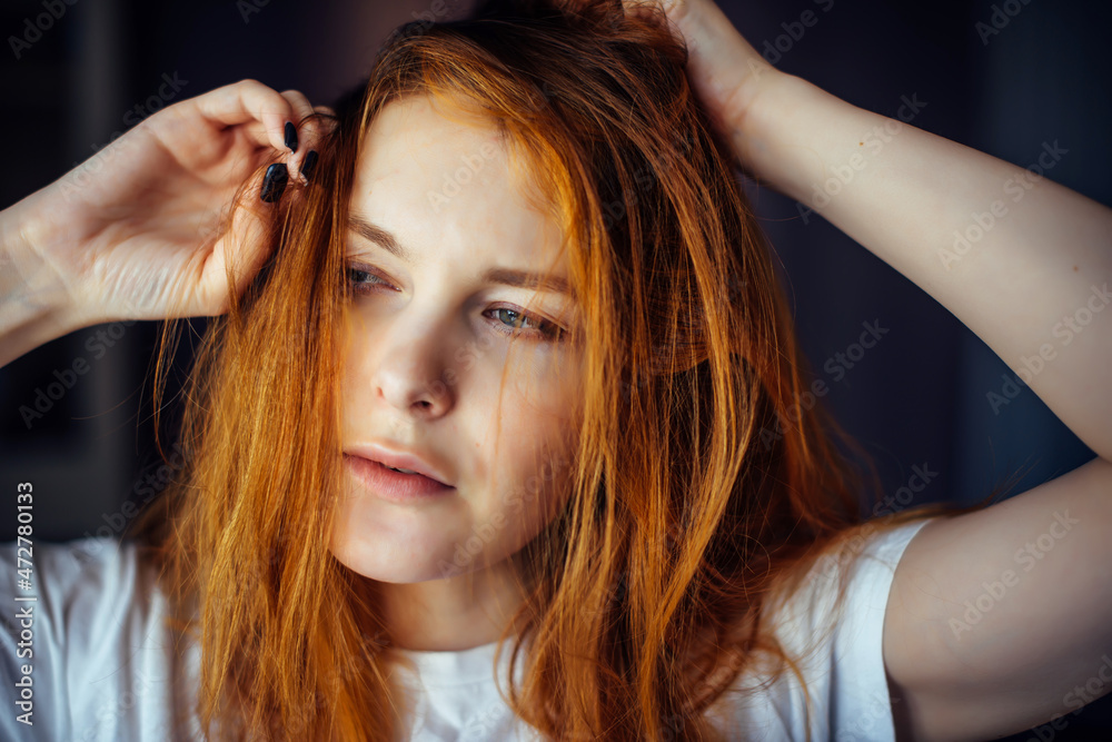 Fototapeta premium Portrait of sexy young woman touching long red hair. Female model posing in the studio, face close-up.
