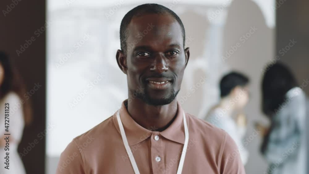 Portrait of cheerful black man with badge looking at camera and smiling on business conference Portrait of cheerful black man with badge looking at camera and smiling on business conference