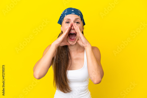 Young English woman isolated on yellow background shouting and announcing something