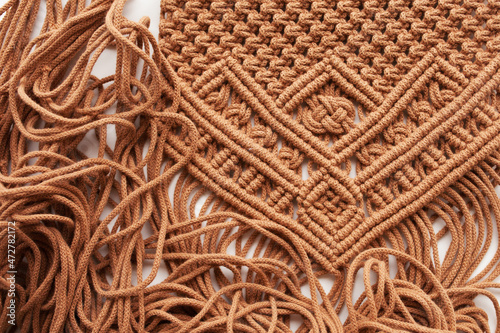 Handmade macrame pattern close up. Macrame braiding and cotton threads on wooden table. Female hobby. ECO friendly modern knitting DIY natural decoration 
