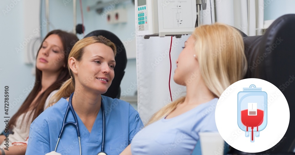 Fototapeta premium Smiling doctor looking donor sitting on chair during blood donation at hospital
