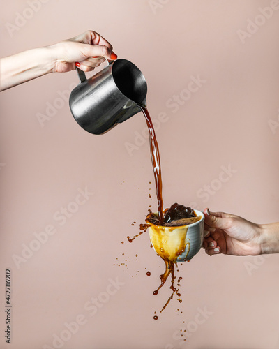 Billede på lærred Coffee is poured into a cup with splashes on a beige background