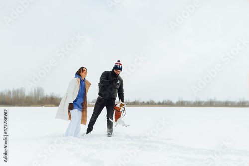 Couple spending time with pet on winter walk. Man and woman playing with cute jack russell dog on in the snow