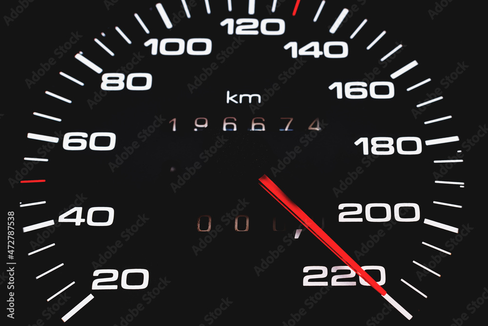 Car speedometer. Auto car speedometer shows 220 km h or miles.Closeup shot,dark black background.Automobile dangerous speed concept Car speedometer. Auto car speedometer shows 220 km h or miles.Closeup shot,dark black background.Automobile dangerous speed concept