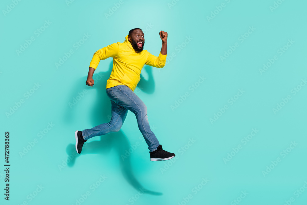 Full size profile side photo of carefree guy jump run fast season bargain isolated over cyan color background Full size profile side photo of carefree guy jump run fast season bargain isolated over cyan color background