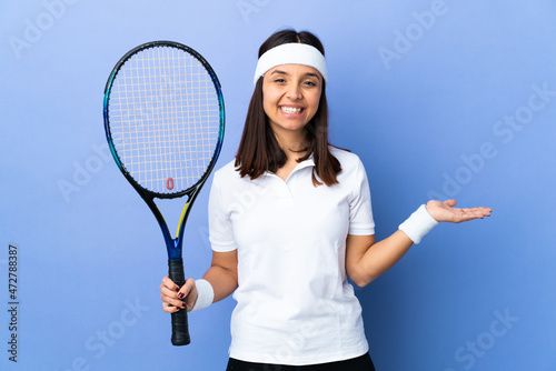 Young woman tennis player over isolated background holding copyspace imaginary on the palm to insert an ad