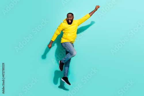 Full size photo of crazy guy jump raise hand up forward rush bargains isolated over cyan color background © deagreez