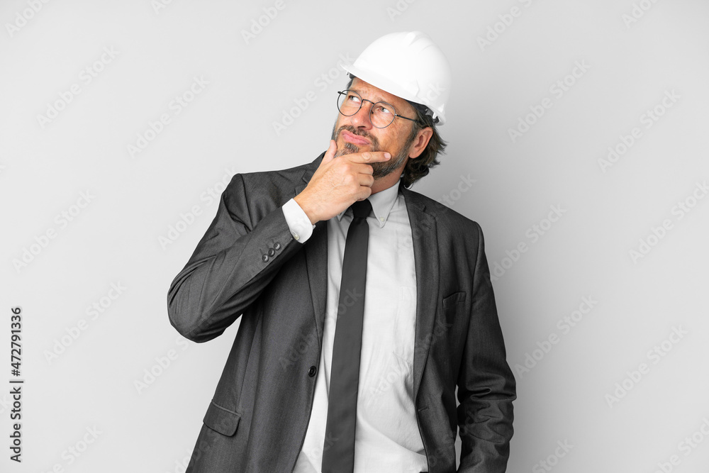Young architect man with helmet over isolated background having doubts and with confuse face expression Young architect man with helmet over isolated background having doubts and with confuse face expression