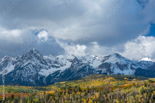 USA, Colorado. San Juan Mountains, Uncompahgre National Forest, Peaks of the Sneffels Range above mixed forest with autumn colored oak and aspen.